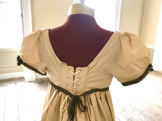 A lady's Regency style day dress in cream silk with black lace trim (lacing at back). Ex London Festival Opera 'Cosi fan tutte'